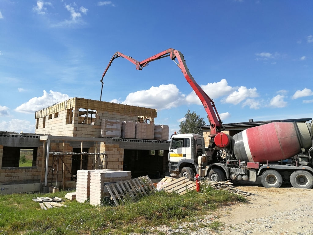 Миксер с бетононасосом заливает дом жидким бетоном