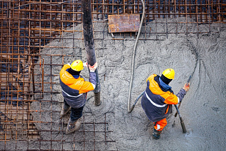 Два бетонщика заливают фундаментную плиту